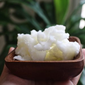 Hand holding Shea butter in the wooden bowl