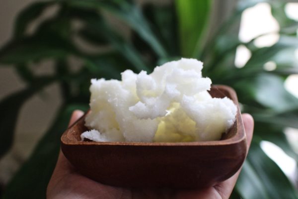 Hand holding Shea butter in the wooden bowl